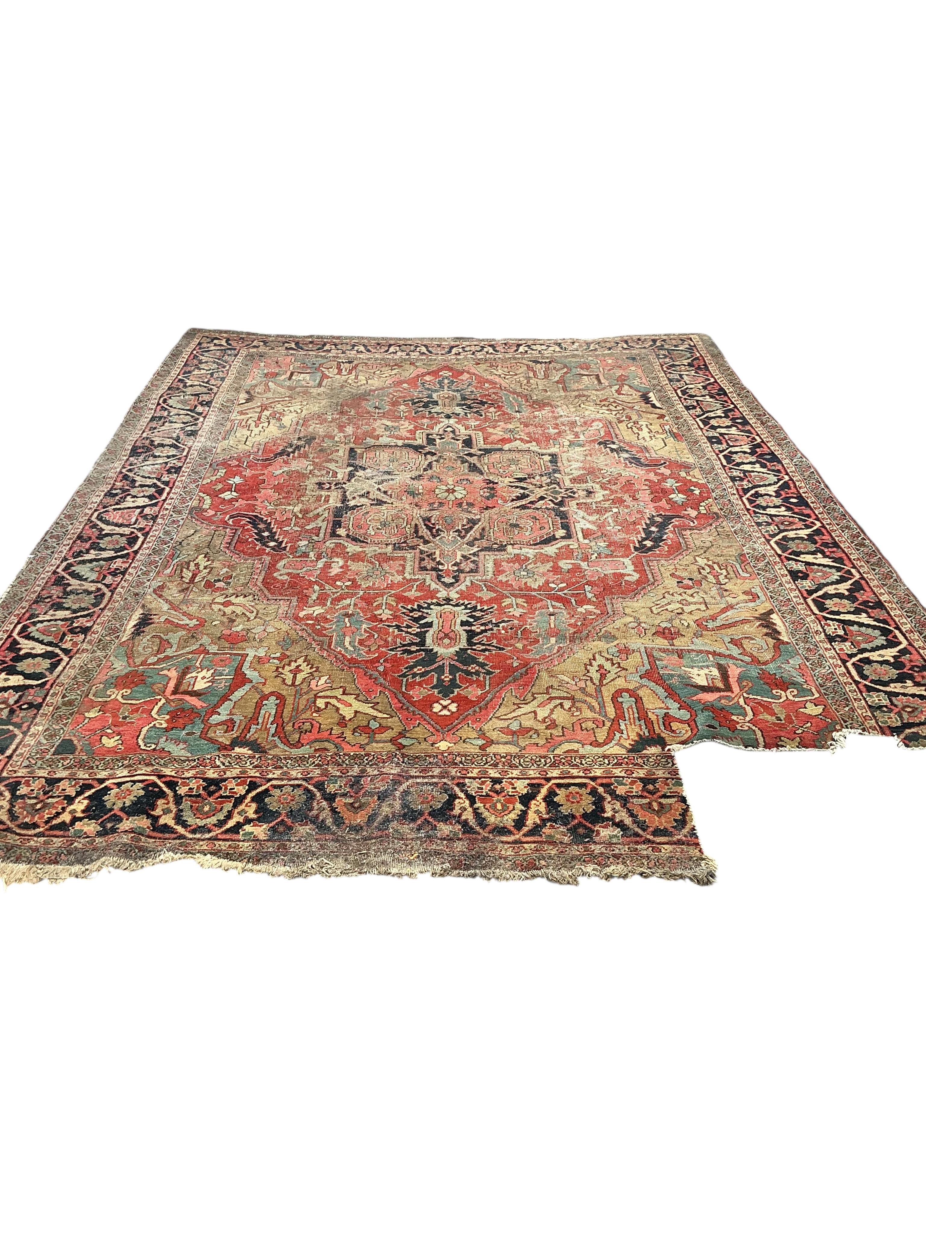 An antique Heriz pink ground carpet, worn and lacking a piece to one corner, 365 x 255cm